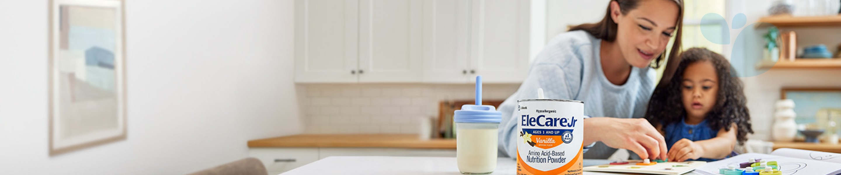 Mom and young daughter playing a puzzle game at the kitchen island. A sippy cup and can of EleCare Jr Vanilla are in front of them.